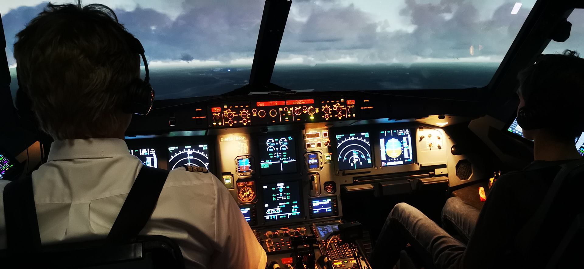 Björn und Willi im Cockpit eines Airbus-Simulators beim Anflug durch die Wolken