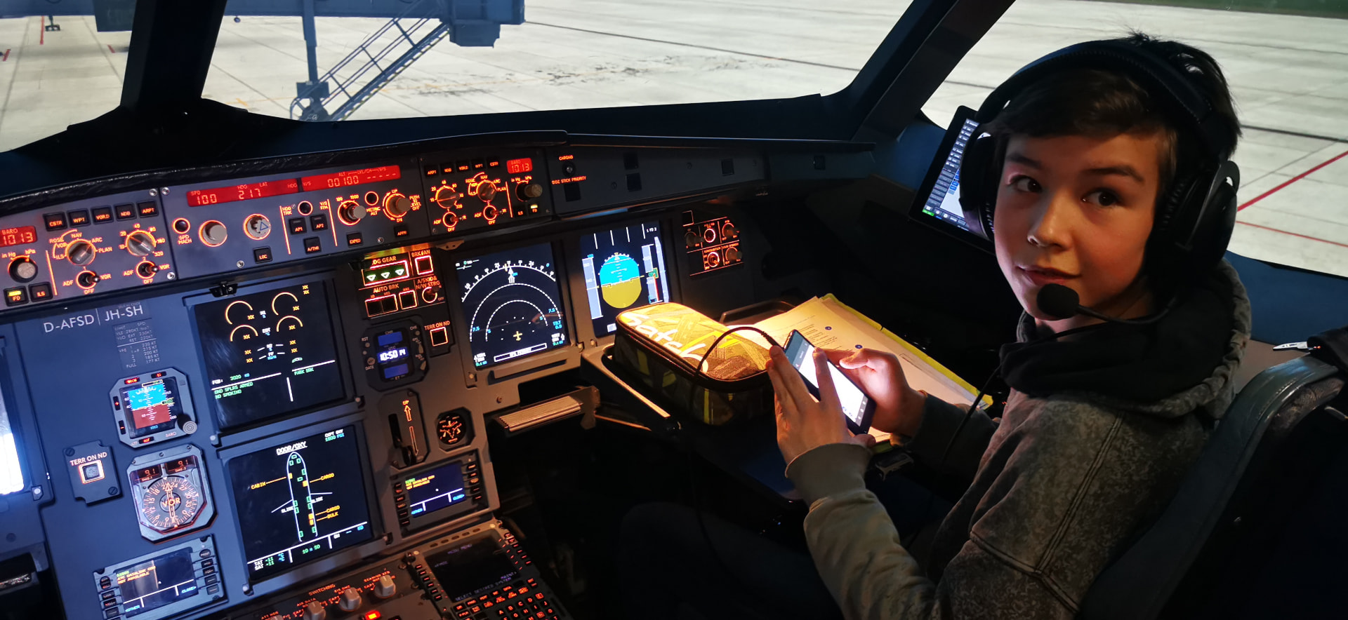 Willi 2021 mit Headset im Airbus-A320-Simulator am Overhead- und Instrumentenpanel
